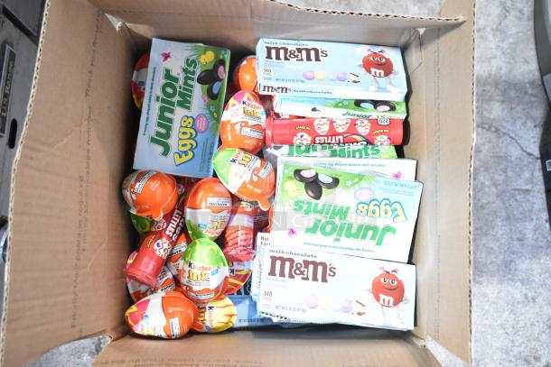 Box containing various candy brands such as Junior Mints, Kinder Joy Eggs, and M&Ms; in new condition.