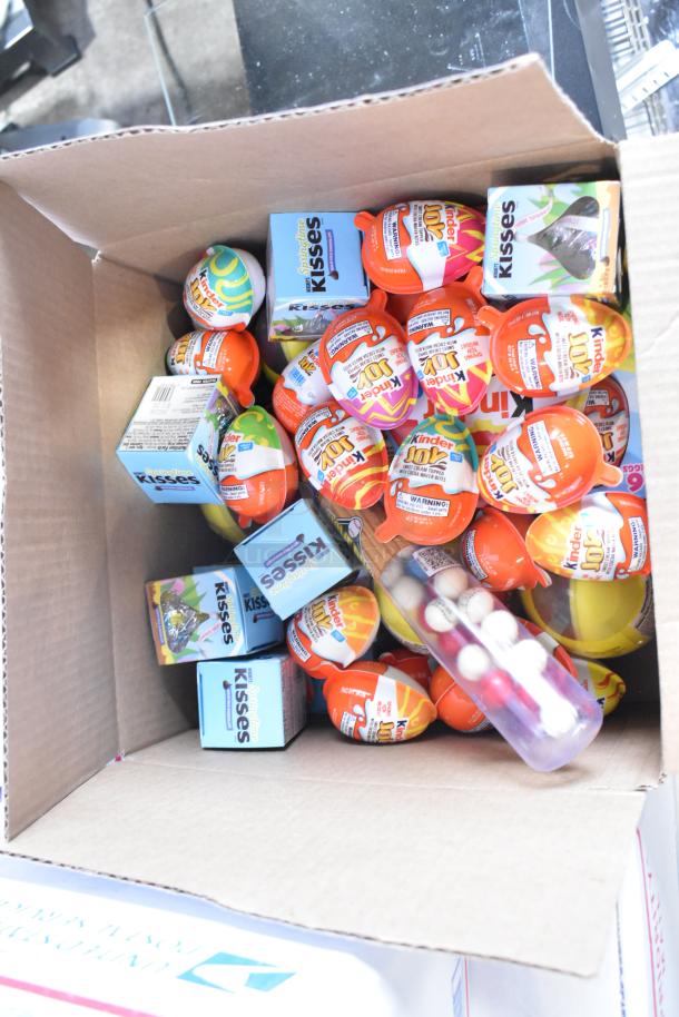 Box containing various candies including Junior Mints, Kinder Joy Eggs, and Kisses. Appears in good condition.