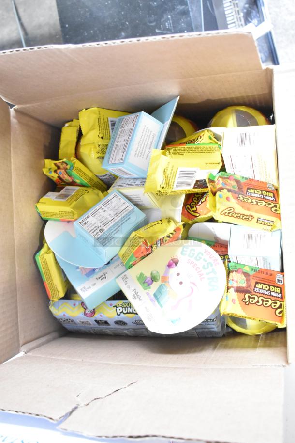 Box containing assorted candies: Junior Mints, Kinder Joy Eggs, Yellow Peeps, and Reese's. Various packaging, brand new condition.