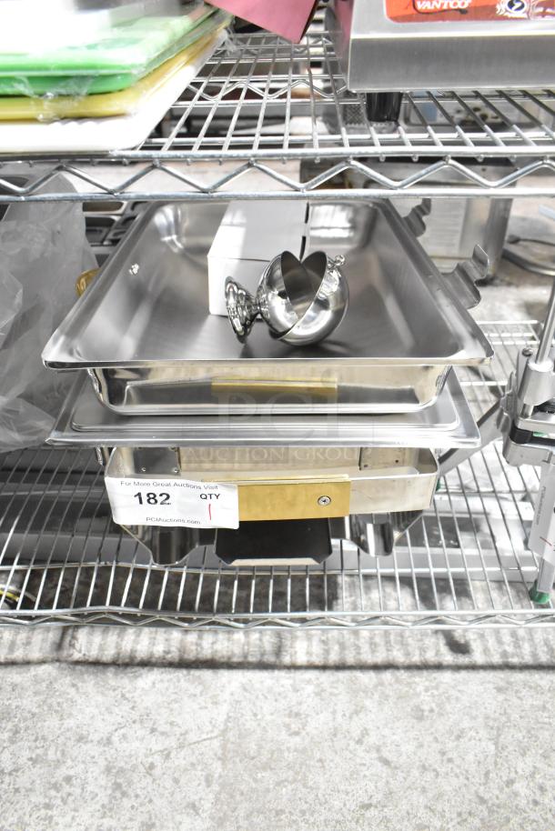 Brand new scratch and dent chafer with metal frame, tray, and lid on metal shelf. Auction tag reads "182, Qty 1".