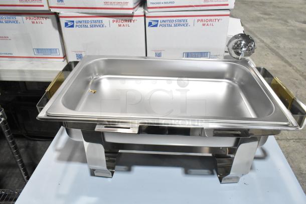 Brand new stainless steel chafer with minor dents, features gold accents, sturdy legs, and a rectangular design.