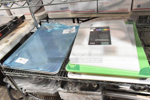 Eight brand new scratch and dent items including baking pans wrapped in blue plastic and white cutting boards.