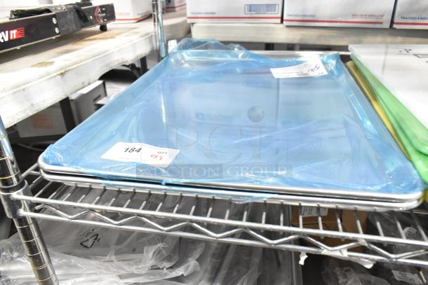 8 brand new scratch and dent items including baking pans and cutting boards. Items are wrapped in blue plastic with labels.