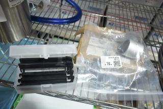 Three new scratch and dent items, including a Regency 600DWF12 dipper well faucet, in packaging on a wire shelf.