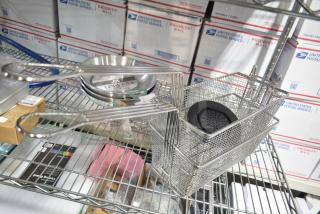 6 brand new scratch and dent items, including three 10" Choice aluminum fry pans and two metal fry baskets, displayed on a shelf.