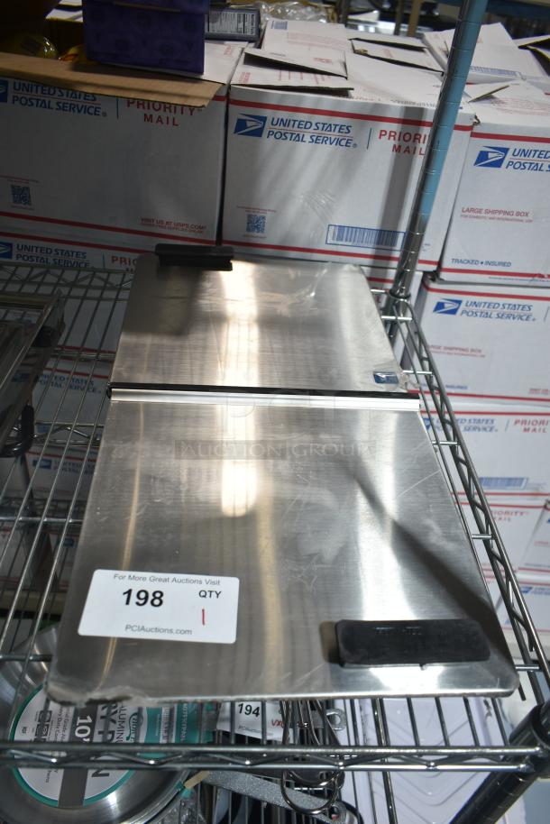 "Brand new scratch and dent Troy Hill center hinge lid on metal shelving, showing minor imperfections. Auction tag reads '198 QTY 1'."