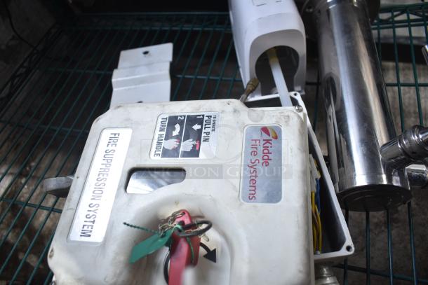 Kidde fire suppression box and beer tap tower displayed on a shelf. Visible labels: "Fire Suppression System," "Kidde Fire Systems," instructions to "Pull Pin" and "Turn Handle."