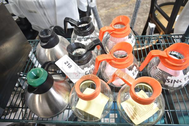 Nine new scratch and dent coffee pots with black and orange handles, various styles, auction tag showing lot 218, bid for quantity 9.