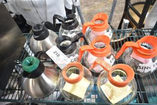 Nine new scratch and dent coffee pots with black and orange handles, various styles, auction tag showing lot 218, bid for quantity 9.