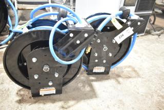 Brand new Regency powder-coated steel air hose reels, two units, minimal scratches, includes hoses, labeled with warnings and quantity tags.