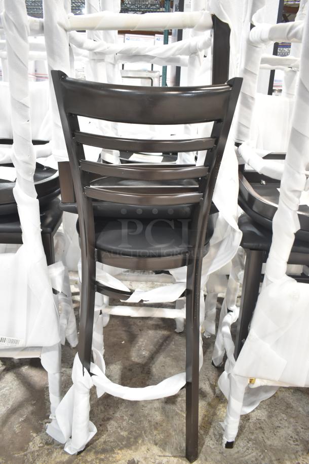 24 new Lancaster Table & Seating Spartan metal ladder back bar stools with dark walnut finish, black vinyl seats, assembled.