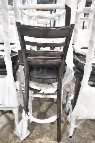 24 new Lancaster Table & Seating Spartan metal ladder back bar stools with dark walnut finish, black vinyl seats, assembled.