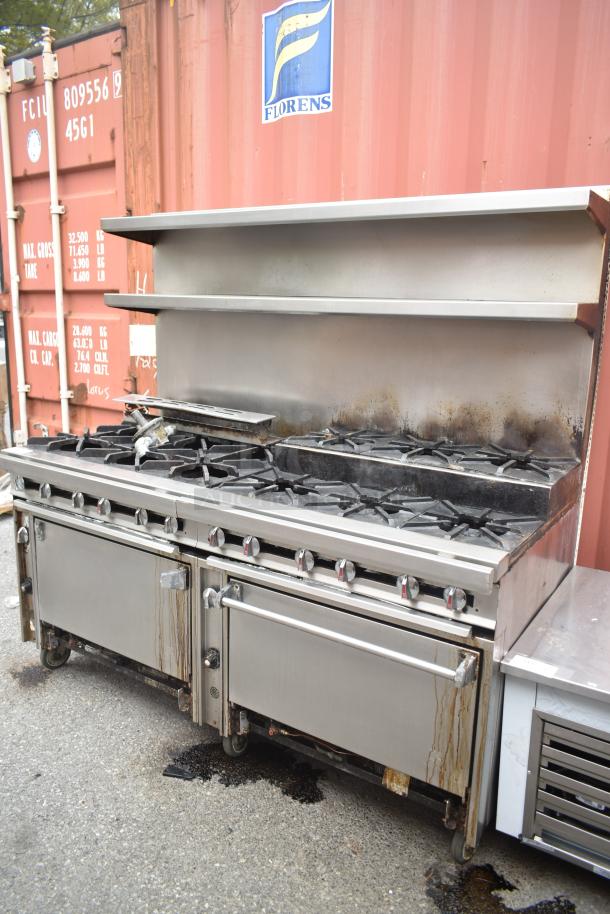Commercial 12-burner gas range with 2 ovens, over shelf, and backsplash on casters; used condition, minor wear.