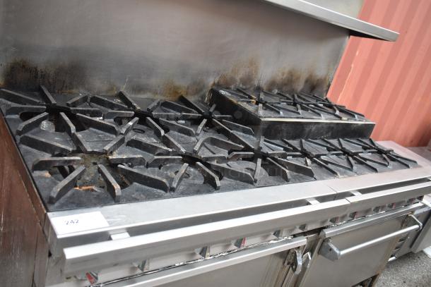 Commercial gas-powered 12-burner range with 2 ovens, over shelf, backsplash, and casters. Used condition.