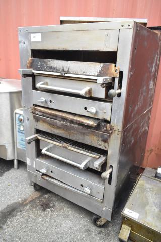 Commercial gas-powered vertical upright broiler on casters with rust and wear, featuring multiple adjustable racks.