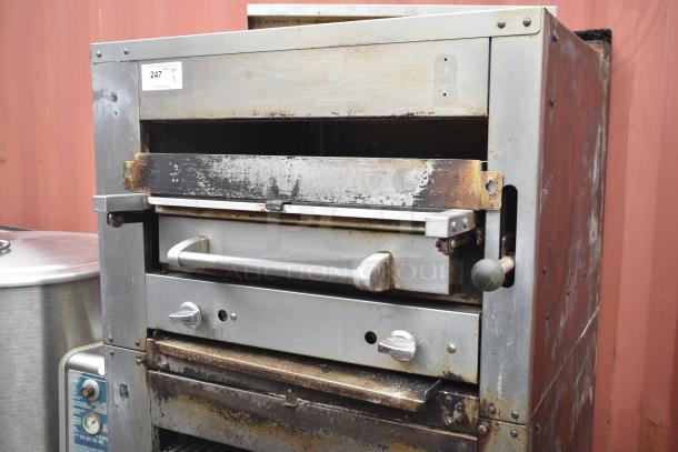 Commercial gas-powered vertical upright broiler on casters, stainless steel, visible wear, tag 247. Ideal for high-volume cooking.