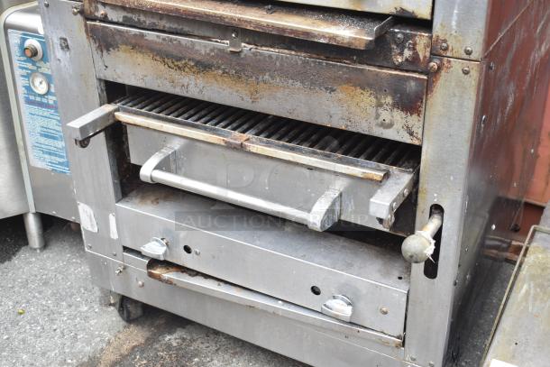 Commercial gas-powered vertical upright broiler on casters, used condition, shows rust and wear, features temperature gauge and control knobs.