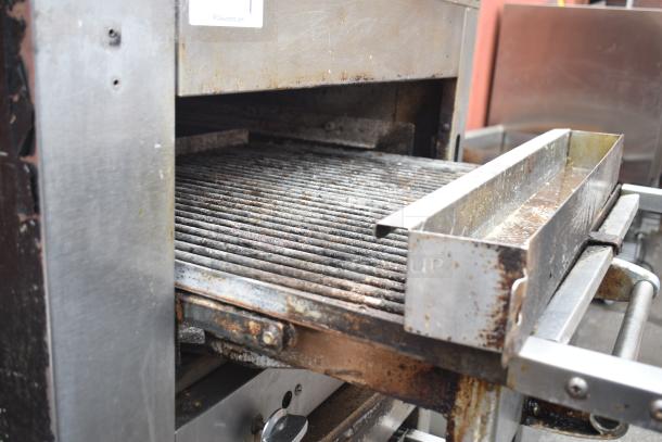Commercial gas powered vertical upright broiler on casters, showing grill surface, signs of wear, and metal housing. Labels and markings visible.