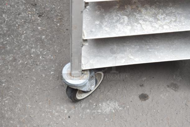 Commercial pan rack on sturdy casters, showing signs of wear, ideal for bakery or restaurant use.