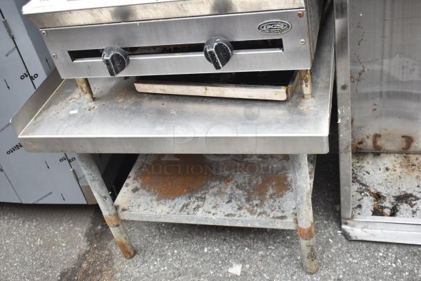 DCS Commercial Gas Charbroiler on stand, visible wear, stainless steel, two knobs, and branded logo plate.