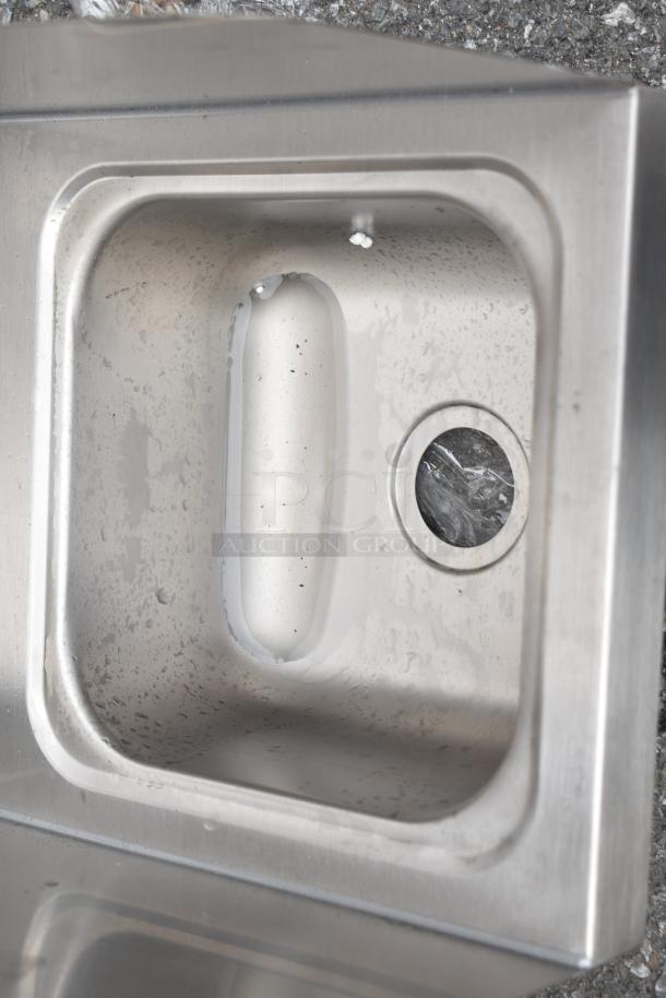 Brand new Regency 600HS12HSP wall-mounted hand sink, 9"x9"x5" with 4" centers, side splash, strainer; scratch and dent condition.