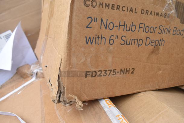 Cardboard box labeled "Commercial Drainage, 2'' No-Hub Floor Sink Body with 6'' Sump Depth, FD2375-NH2," showing damage.