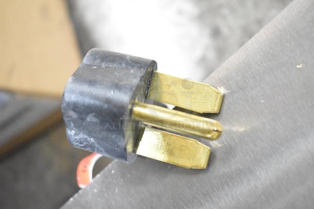 Close-up of a power plug with brass prongs for a Vollrath Cayenne STA8002 2 Burner Electric Hot Plate, 208/240 Volts.