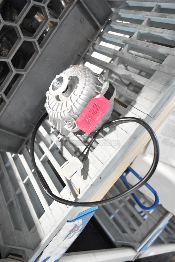 BRAND NEW Avantco 17816223 Fan Motor, 120V, 33W, with visible scratches. Pink label attached. Placed on a metal grate.
