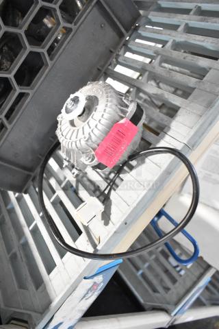 BRAND NEW Avantco 17816223 Fan Motor, 120V, 33W, with visible scratches. Pink label attached. Placed on a metal grate.