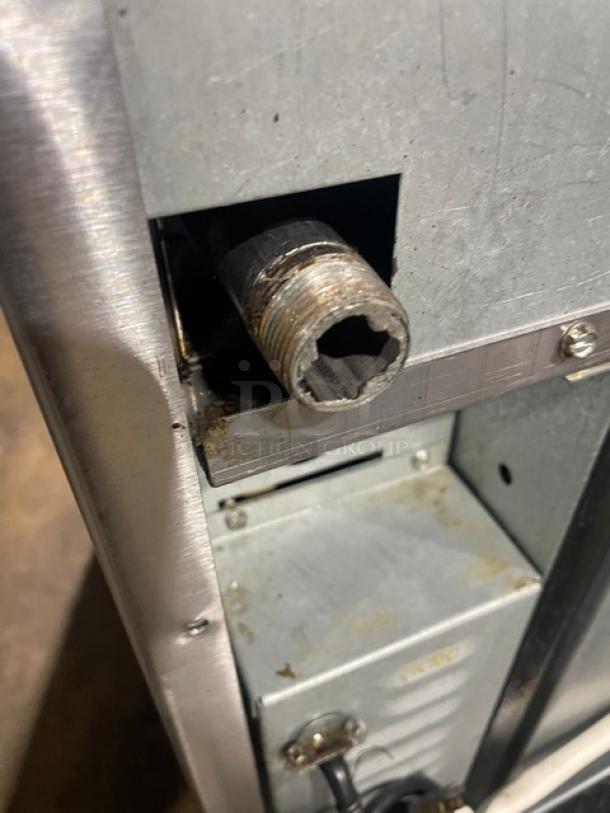 Imperial commercial stainless steel gas-powered radiant char broiler range/convection oven combo, featuring a backsplash and wired oven rack, on casters. Visible wear and connectors.