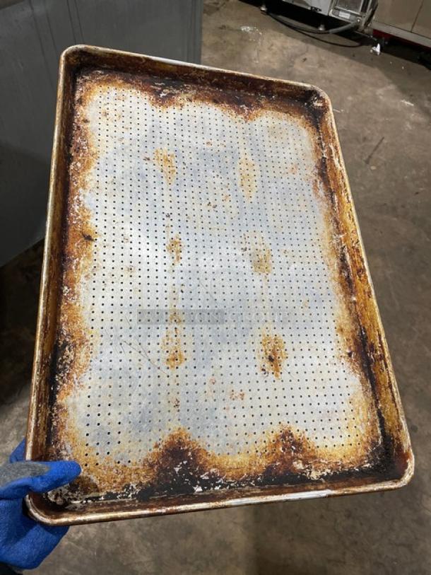 Commercial perforated sheet pan, well-used, visible rust and wear, ideal for professional baking, durable construction.