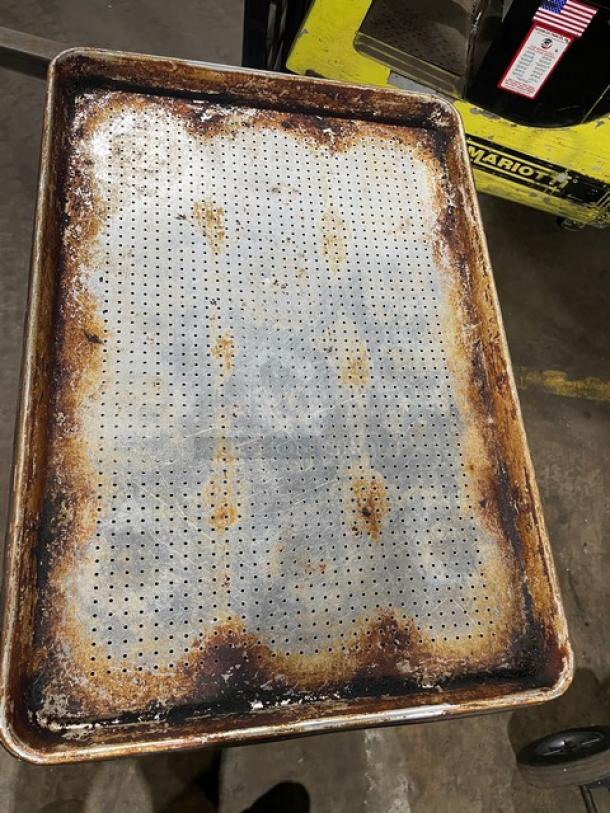 Commercial perforated sheet pan, heavily worn with rust and discoloration. Ideal for high-volume baking despite used condition.