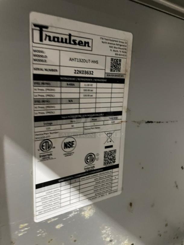 Traulsen AHT132DUTHHS stainless steel single section reach-in refrigerator with wired racks, model and serial label shown.