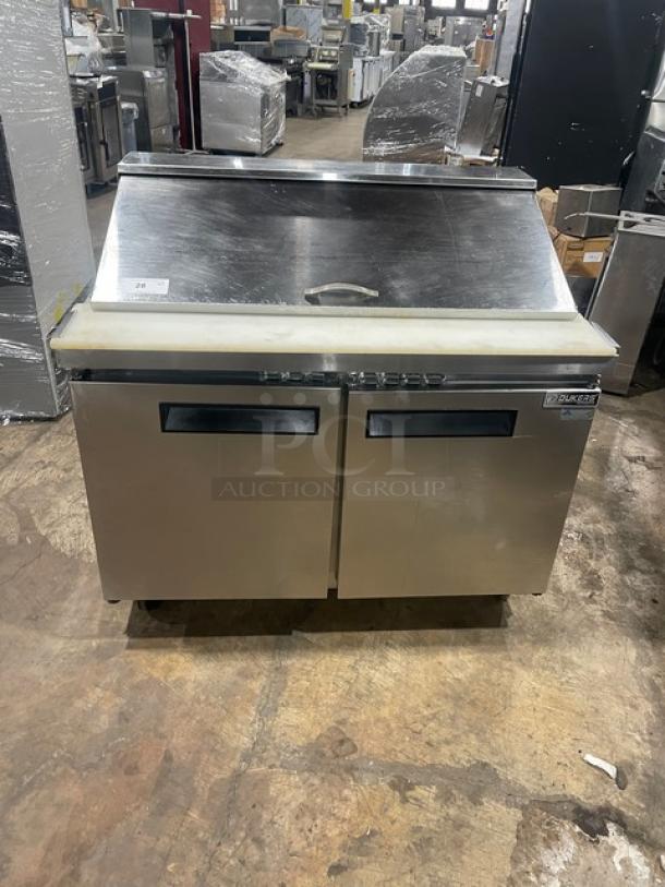 Dukers DSP48 stainless steel two-door refrigerated prep table with cutting board, poly-coated rack, on casters.