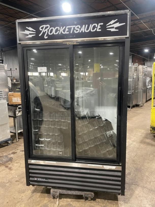 True GDM-41 commercial black double glass sliding door refrigerator with pusher glide bottle organizer. Serial No: 570537.