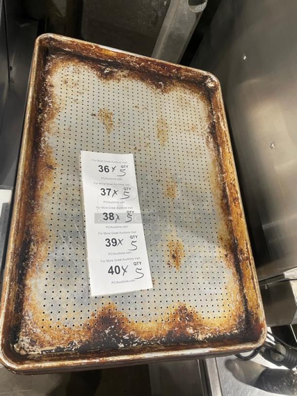 Commercial perforated sheet pan with visible rust, used condition. Includes Auction tags noting bid increments and quantities.