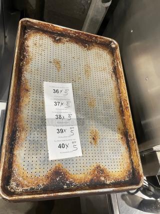 Commercial perforated sheet pan with visible rust, used condition. Includes Auction tags noting bid increments and quantities.