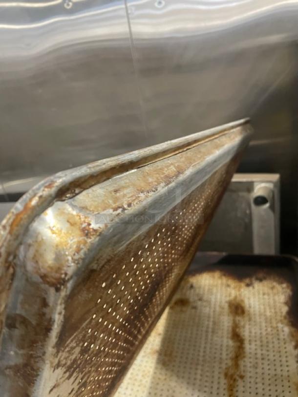 Commercial perforated sheet pan in used condition, showing rust and wear. Ideal for bakery or kitchen use.