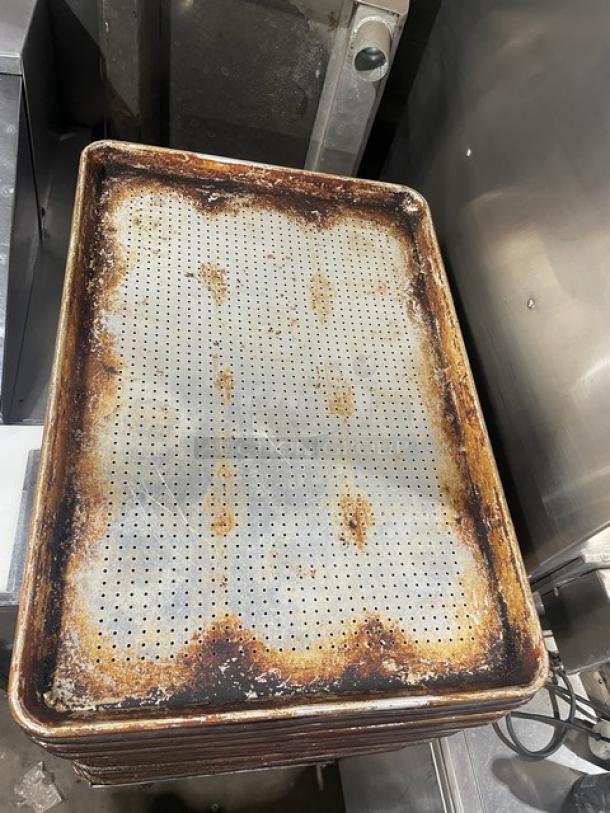 Commercial perforated sheet pan, well-used with visible rust and wear. Ideal for baking and roasting. Stackable.