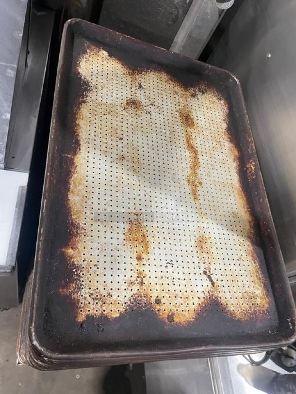 Commercial perforated sheet pan with visible wear and rust; ideal for baking, enhancing heat circulation.