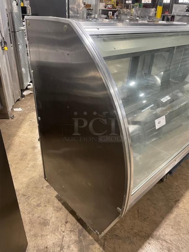 Commercial stainless steel bakery display case with curved glass, multi-tier shelves, rear sliding glass doors, and minor wear.