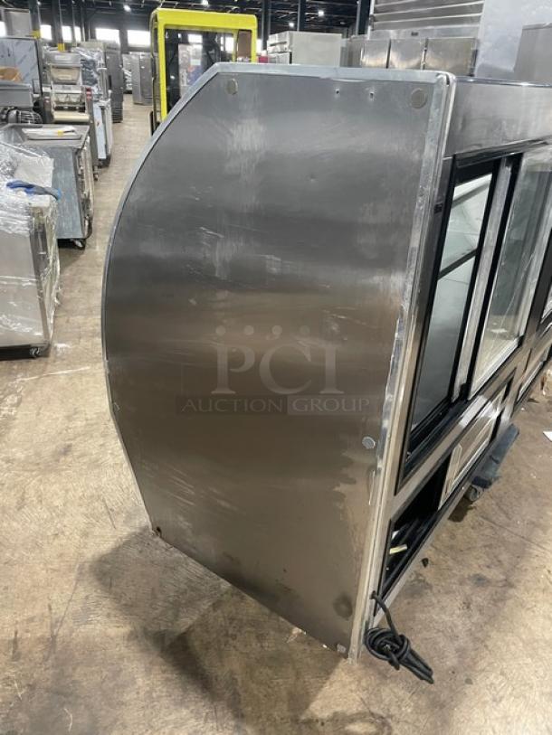 Commercial stainless steel curved glass bakery display case, multi-tiered, with rear access sliding glass doors, used condition.