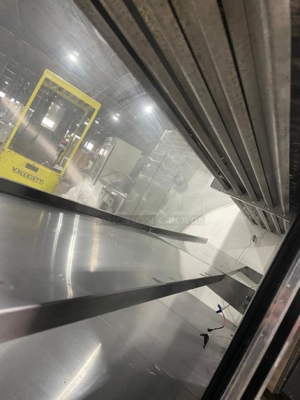 Commercial stainless steel bakery display case with curved glass, multi-tier shelves, and rear access sliding doors.