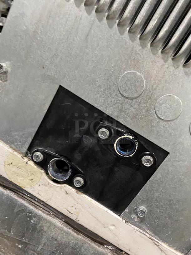 Close-up of Manitowoc IY1106A-261 ice machine connector ports on stainless steel body, showing mounting screws and metal surface.