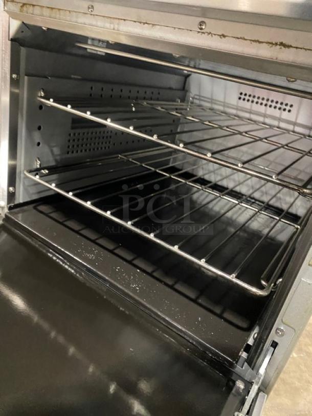 Cookline ER24-208 commercial range/oven combo with stainless steel finish, visible wired rack interior, and backsplash.
