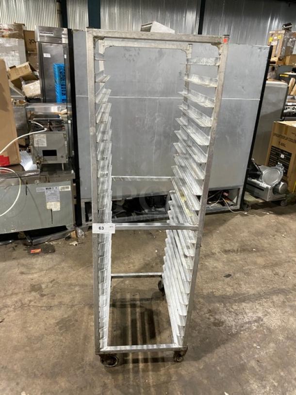 Commercial stainless steel sheet pan rack on casters, used condition, multiple slots for pans, tag number 63 visible.