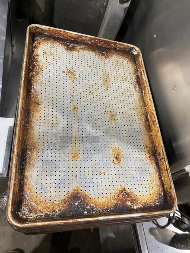 Commercial perforated sheet pan, used condition, visible wear and rust. Ideal for baking, provides even heat distribution.