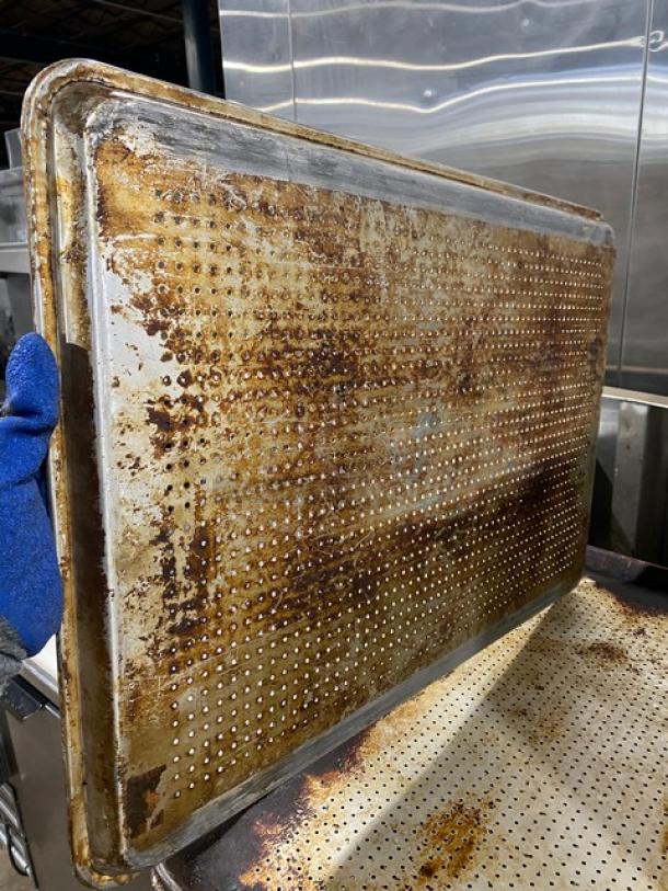 Commercial perforated sheet pan with visible wear and discoloration, ideal for baking. Auction allows 5X bids.