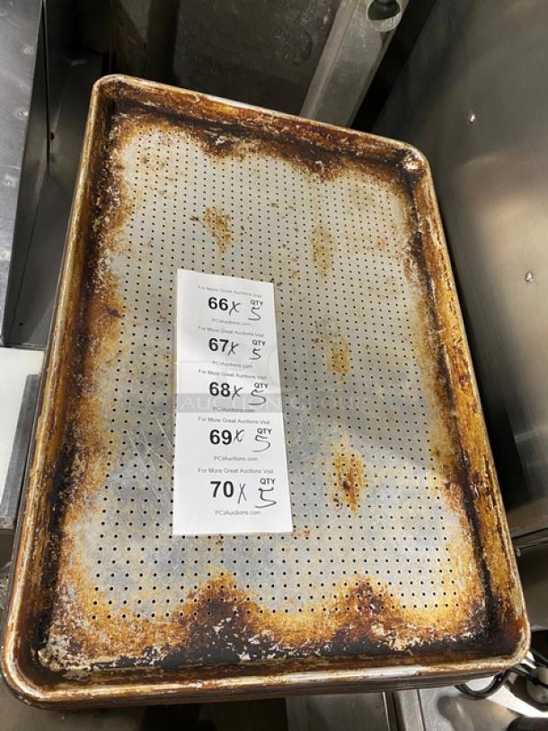 Commercial perforated sheet pan with visible wear, rust, and perforations for even baking. Includes auction tags.