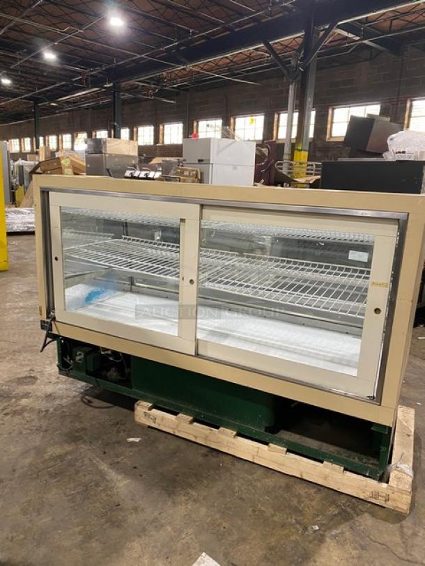 Schmidt curved glass refrigerated display case with multi-tier shelves, rear sliding glass doors, and poly-coated wire rack.